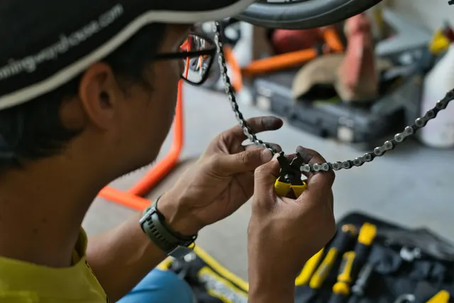 Mécanicien manipulant une chaîne de vélo avec une pince à attache rapide, dans un atelier
